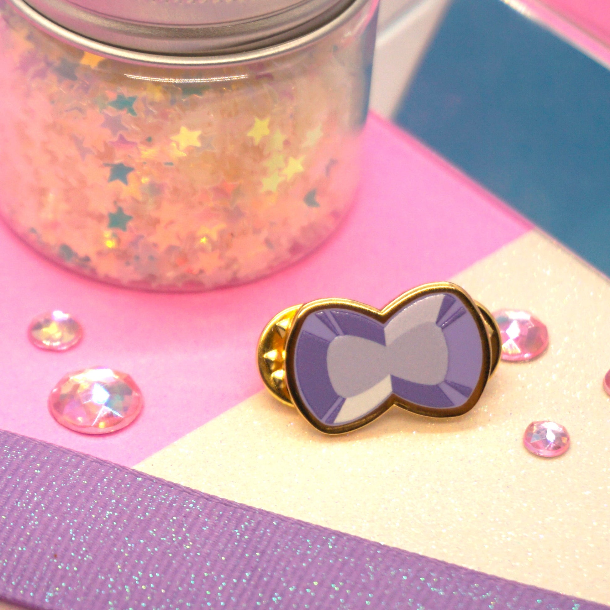 Bow-shaped pin with purple gem and gold border.